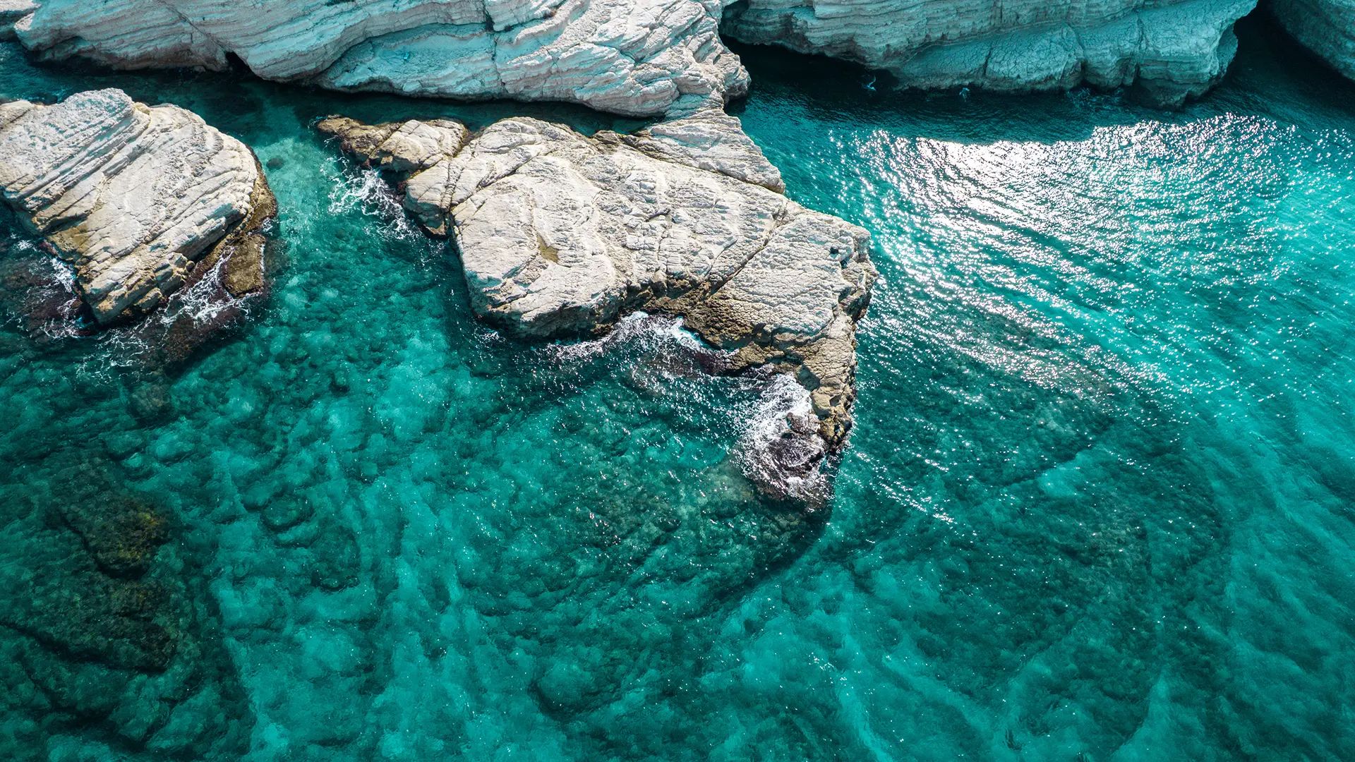 Aerial view of white rock formations in turquoise water north of Latakia